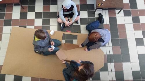 Students cutting paper on the floor