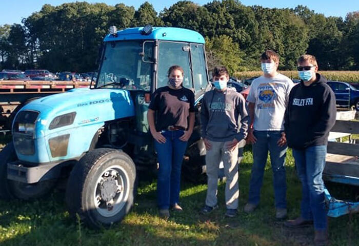 Students posing in front of tractor